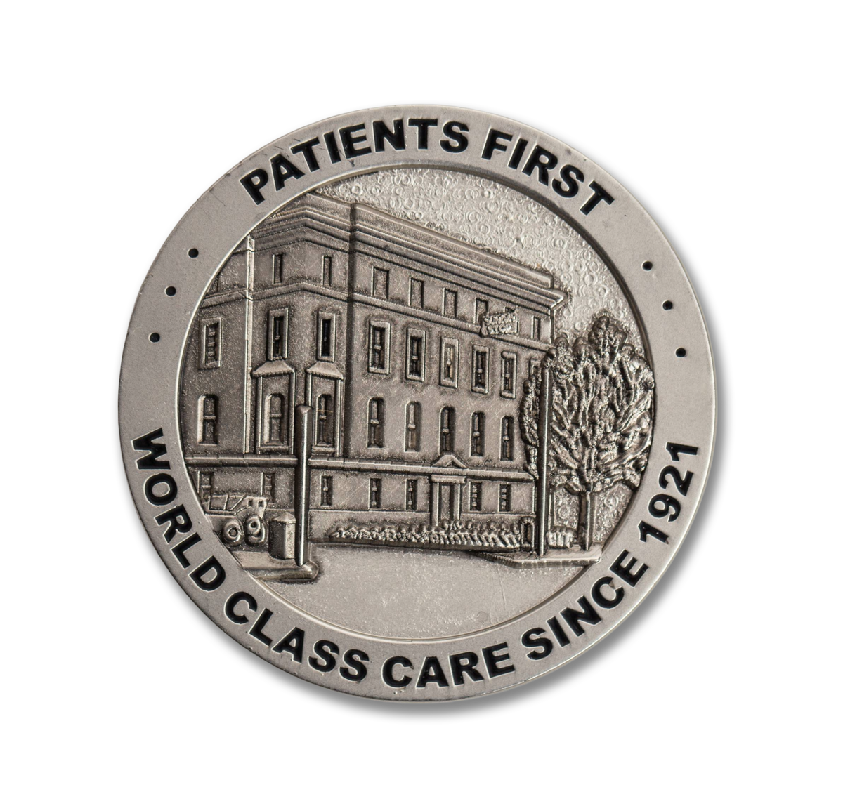 Medallion with building illustration and text 'Patients First, World Class Care Since 1921' on a white background